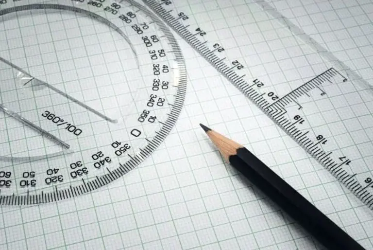 sharpened pencil, ruler and protractor on squared paper
