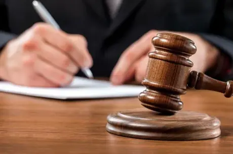 A gavel and lawyer's hand making notes