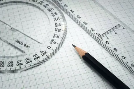 sharpened pencil, ruler and protractor on squared paper